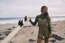 A woman wearing a wetsuit and holding a surfboard