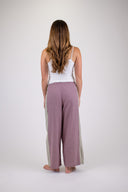 A woman wearing the Atmosea Patchwork pants against a white background, posing from the back. 
