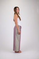A woman wearing the Atmosea Patchwork pants against a white background, posing from the side. 