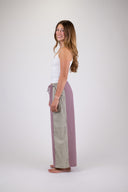 A woman wearing the Atmosea Patchwork pants against a white background, posing from the side. 