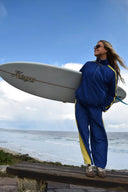 Lifestyle photo of the Atmosea Après Surf Panel Pant with a surfboard.