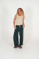 A model wearing the Atmosea Après Surf Pants in forest green cotton terry towelling with a relaxed wide-leg fit, elastic drawstring waist, and sporty canvas side stripes.