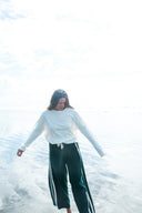 A model outside wearing the Atmosea Après Surf Pants in forest green cotton terry towelling with a relaxed wide-leg fit, elastic drawstring waist, and sporty canvas side stripes.
