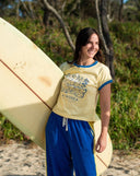 Lifestyle photo of the Atmosea Dressing Mermaids Artist Cap Sleeve Tee with a surfboard.