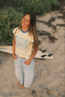 Lifestyle photo of the Atmosea Dressing Mermaids Artist Cap Sleeve Tee on the beach.