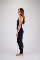 A woman wearing the Atmosea long jane wetsuit in black against a white background, posing to the side. 