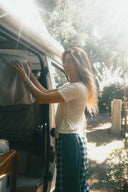 A woman smiling outdoors wearing the Atmosea Patchwork Pants in Turquoise Check featuring a relaxed wide-leg fit and colorful checkered cotton fabric.