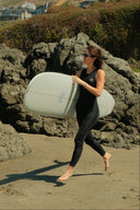 Lifestyle photo of the Atmosea Yulex Long Jane 2mm carrying a surfboard.