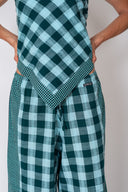 An upclose look of a model wearing the Atmosea Patchwork Pants in Turquoise Check featuring a relaxed wide-leg fit and colorful checkered cotton fabric.