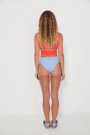 A model wearing the Salt Gypsy Drifter 2.0 reversible swim bottoms in Baby Blue and Chilli Red from the back
