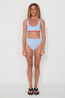 A model wearing the Salt Gypsy Drifter 2.0 reversible swim bottoms in Baby Blue and Chilli Red from the front