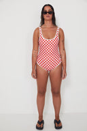 A front view of a model in a studio wearing the Salt Gypsy Everyday One Piece in Chilli Checkers