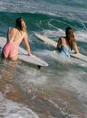 A model in the water wearing the Salt Gypsy Everyday One Piece in Chilli Checkers