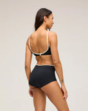 The back view of a model wearing the Seea Maggie Bikini Top in Black featuring textured recycled bouclé fabric, adjustable straps, and supportive bralette design.
