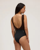 Back view of a model wearing the Seea Pacific One Piece swimsuit in Black/Cappuccino featuring a high neckline, deep V-back, and cheeky coverage.