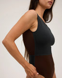 Up close view of the side of a model wearing the Seea Pacific One Piece swimsuit in Black/Cappuccino featuring a high neckline, deep V-back, and cheeky coverage.
