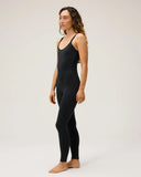 A side view of a model wearing the Seea Penelope Bodysuit in Black featuring full-length surf leggings, adjustable straps, and recycled C-Skin fabric.