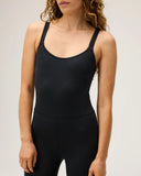 An upclose view of a model wearing the Seea Penelope Bodysuit in Black featuring full-length surf leggings, adjustable straps, and recycled C-Skin fabric.