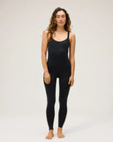 A model wearing the Seea Penelope Bodysuit in Black featuring full-length surf leggings, adjustable straps, and recycled C-Skin fabric.