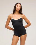 A front view of a model in a studio wearing the Seea Rosita One Piece swimsuit in Black featuring white contrast trim, adjustable straps, and a low scoop back.