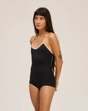 A model wearing the Seea Rosita One Piece swimsuit in Black featuring white contrast trim, adjustable straps, and a low scoop back.
