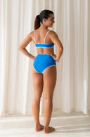 Side view of model wearing Island Bikini Bottom in Nineties Blue in a studio