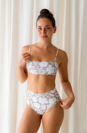 Up close front view of model wearing Lucky Bikini Bottom in Aloha Dune Print in a studio