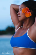 Up close view of model wearing River Nineties Blue Bikini Top outside with a flower in her hair