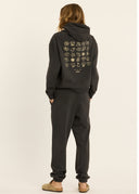 A back view of a model wearing the Sisstr Coast to Coast Fleece Jogger in Vintage Black featuring a relaxed fit, elastic waistband, cuffed ankles, and coastal-inspired leg graphics.