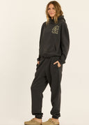 A side view of a model wearing the Sisstr Coast to Coast Fleece Jogger in Vintage Black featuring a relaxed fit, elastic waistband, cuffed ankles, and coastal-inspired leg graphics.