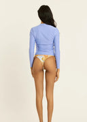 The back view of a model wearing the Sisstr Seeker Solid women’s surf rashguard in Blissful Blue