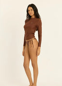 Side view of a model wearing the Sisstr Seeker Solid women’s surf rashguard in Kona brown