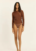 A model wearing the Sisstr Seeker Solid women’s surf rashguard in Kona brown