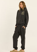 A model wearing the Sisstr Surf Check Fleece Hoodie in Vintage Black featuring front and back graphic prints, relaxed fit, and kangaroo pocket.