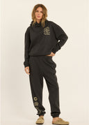 The front view of a model wearing the Sisstr Surf Check Fleece Hoodie in Vintage Black featuring front and back graphic prints, relaxed fit, and kangaroo pocket.
