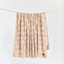 Slowtide Hau Oversized Beach Blanket hanging to showcase its lightweight woven fabric and floral pattern.