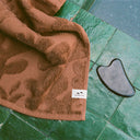 Reverse side of the Slowtide Sunny Sculpted Towel draped over the edge of a pool.